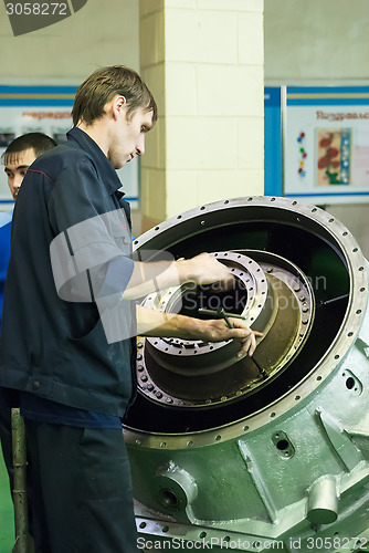 Image of Mechanic assembles part for aviation engine