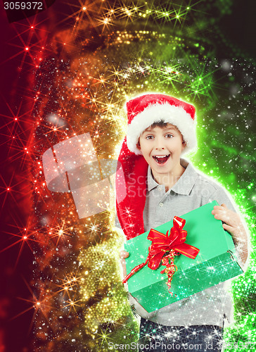 Image of happy boy in santa hat surprised by christmas present