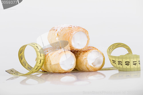 Image of concept of slimming, cakes with measuring tape