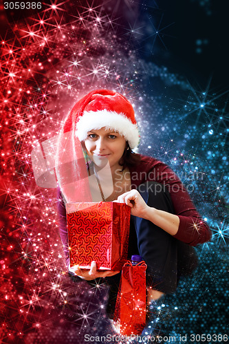 Image of Beautiful middle age woman in red party santa hat sitting with gifts, with abstract background