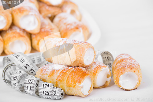 Image of concept of slimming, cakes with measuring tape