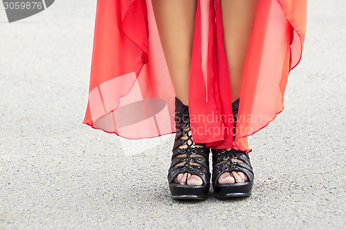 Image of Slender woman legs on heels and red dress 