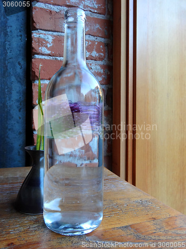 Image of Still-life of a bottle and a flower in a vase