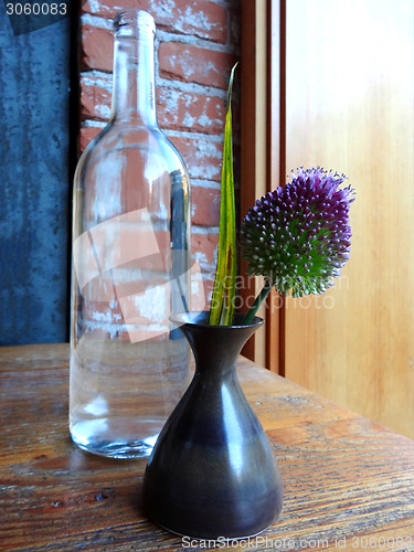 Image of Still-life of a bottle and a flower in a vase