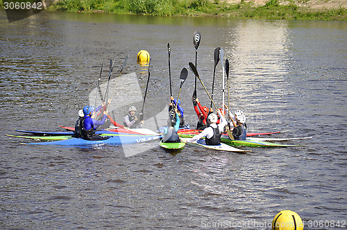 Image of People on kayaks lifted oars up.