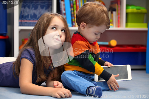 Image of Disappointing girl with her little brother using a tablet comput