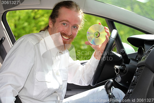 Image of driver with CD, playing music in the car