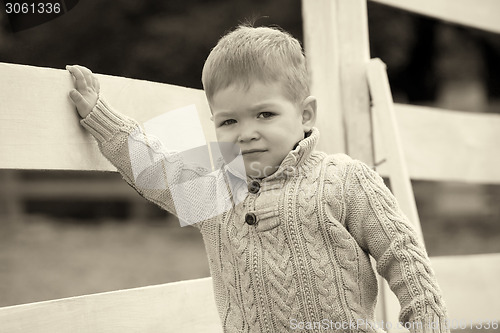 Image of 2 years old Baby boy on the a white picket fence beside the hors