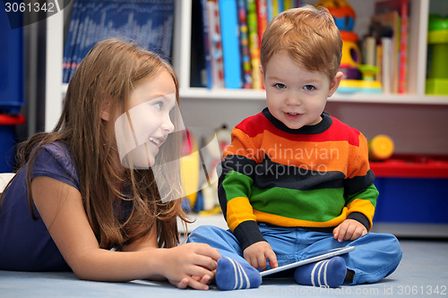 Image of Girl with her little brother fun using a digital tablet computer