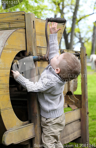 Image of 2 years old curious Baby boy managing with old agricultural Mach