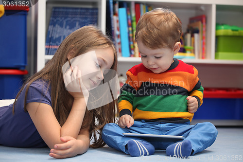 Image of Girl with her little brother fun using a digital tablet computer