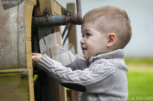 Image of 2 years old curious Baby boy managing with old agricultural Mach