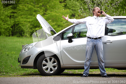 Image of Driver furious with mobile phone a broken car by the road