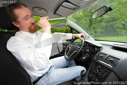 Image of Drunk man in car with a bottle alcohol