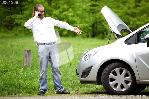 Image of Driver furious with mobile phone a broken car by the road