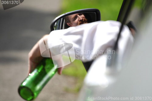 Image of Drunk man in car with a bottle alcohol