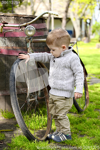 Image of 2 years old curious Baby boy walking around the old bike 