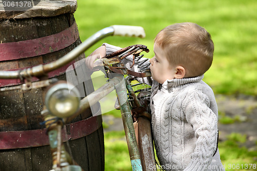 Image of 2 years old curious Baby boy walking around the old bike 