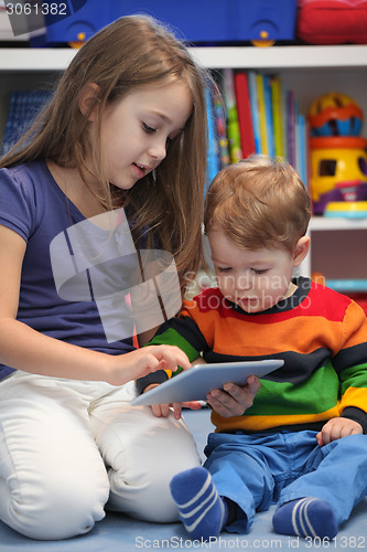 Image of Girl with her little brother fun using a digital tablet computer