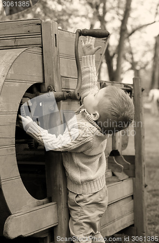 Image of 2 years old curious Baby boy managing with old agricultural Mach