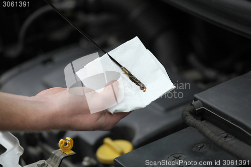 Image of Auto mechanic checking engine oil dipstick in car