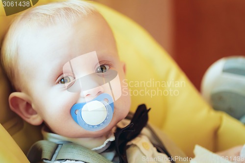 Image of Pretty Baby Boy Sitting In Yellow Seat With Soother