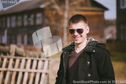 Image of Young Handsome Man Staying Near Old Wooden House In Autumn Or Sp