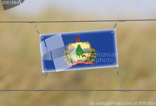 Image of Border fence - Old plastic sign with a flag