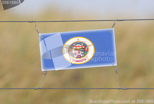 Image of Border fence - Old plastic sign with a flag