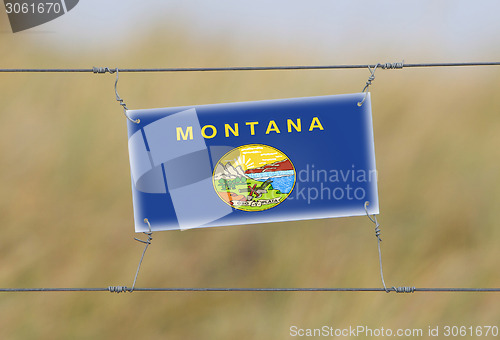 Image of Border fence - Old plastic sign with a flag