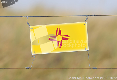 Image of Border fence - Old plastic sign with a flag