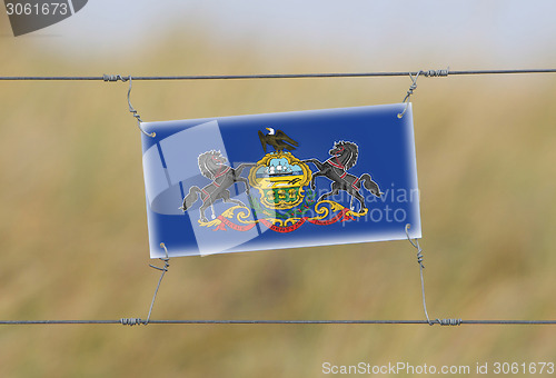 Image of Border fence - Old plastic sign with a flag