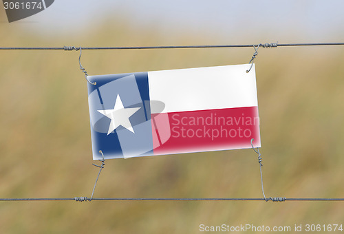 Image of Border fence - Old plastic sign with a flag