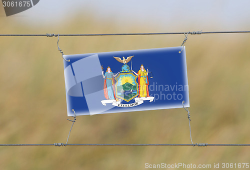 Image of Border fence - Old plastic sign with a flag