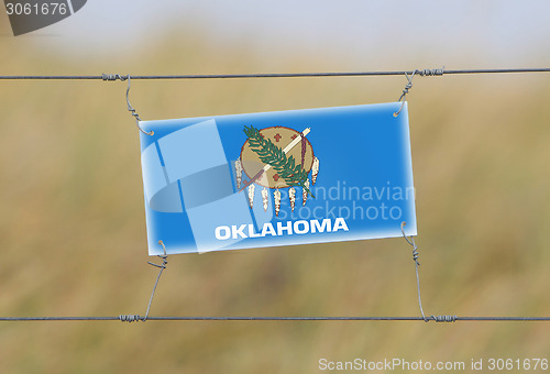 Image of Border fence - Old plastic sign with a flag