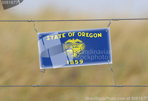 Image of Border fence - Old plastic sign with a flag