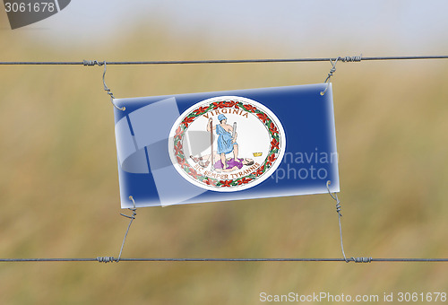 Image of Border fence - Old plastic sign with a flag