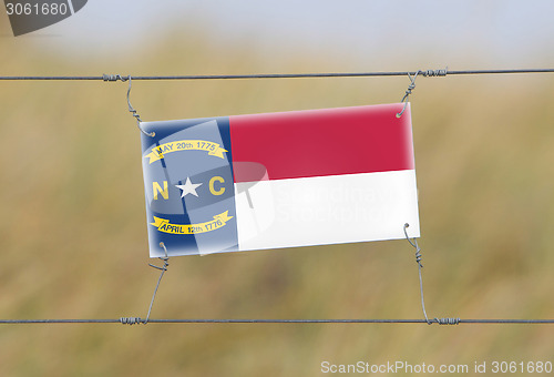 Image of Border fence - Old plastic sign with a flag