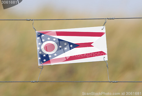 Image of Border fence - Old plastic sign with a flag