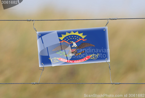 Image of Border fence - Old plastic sign with a flag