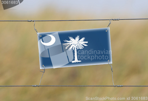 Image of Border fence - Old plastic sign with a flag