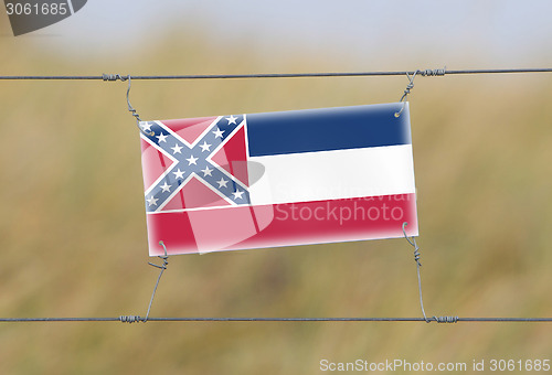 Image of Border fence - Old plastic sign with a flag