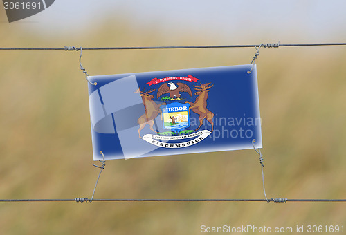 Image of Border fence - Old plastic sign with a flag