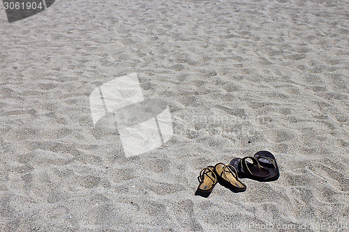 Image of His and hers flip flop sandals on the sandy beach