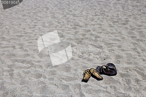 Image of His and hers flip flop sandals on the sandy beach