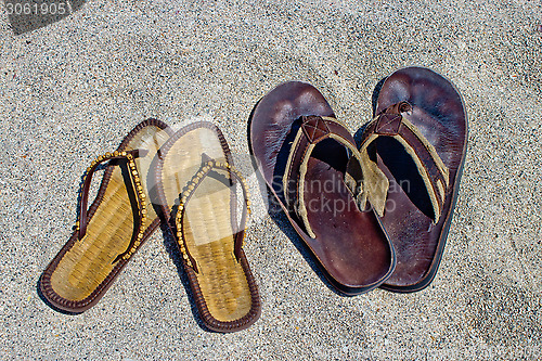 Image of His and hers flip flop sandals on the sandy beach