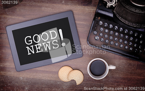 Image of Tablet touch computer gadget on wooden table, good news