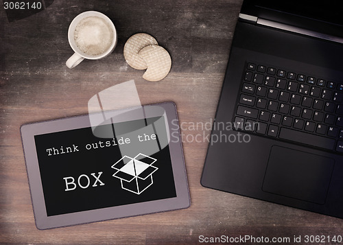 Image of Tablet touch computer gadget on wooden table, think outside the 