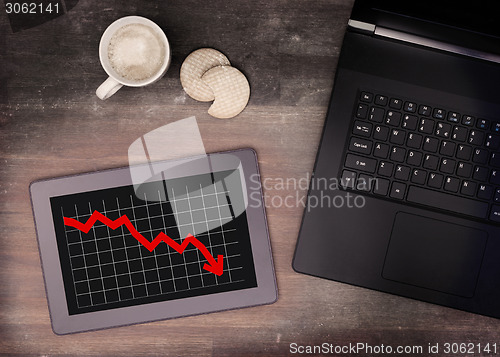 Image of Tablet touch computer gadget on wooden table, graph negative