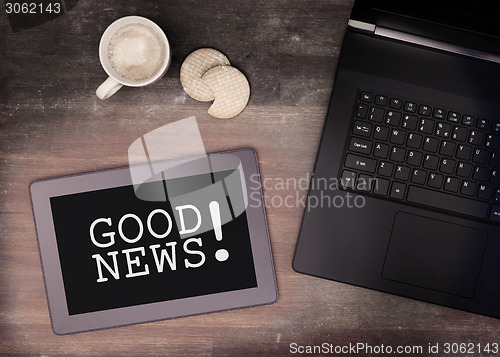 Image of Tablet touch computer gadget on wooden table, good news